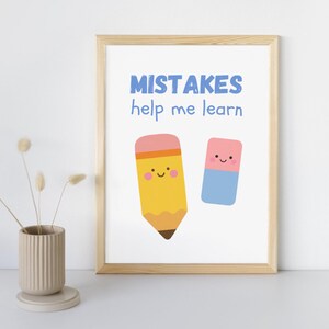 May include: A framed print with the text "MISTAKES help me learn" in blue. The print features a yellow pencil and a blue eraser, both with smiling faces. The frame is made of light-coloured wood.