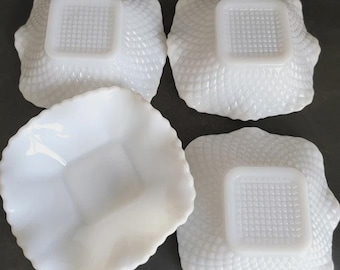 May include: A set of four square white milk glass bowls featuring a textured diamond pattern on the exterior. Three bowls are positioned upside down, revealing a square base with a grid design, while one bowl is placed right side up.