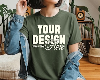 May include: Olive green t-shirt with the text "YOUR DESIGN Here" in white. The shirt is a crew neck style and is being worn with a denim jacket. The words "HIGH-QUALITY MOCKUPS" are below the words "YOUR DESIGN".