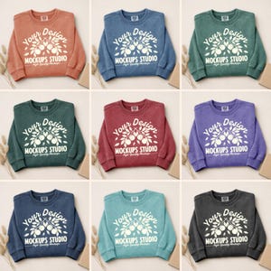 May include: Nine crewneck sweatshirts in various colors, including rust, blue, green, burgundy, purple, navy, teal, and charcoal. Each sweatshirt features the text "Your Design" above a botanical illustration and the words "MOCKUPS STUDIO" below.
