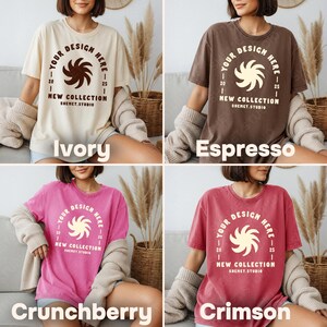 May include: Four t-shirts in ivory, espresso, crunchberry, and crimson. Each shirt has a circular design with the text "YOUR DESIGN HERE" and "NEW COLLECTION SHEMET.STUDIO". The shirts are short-sleeved and appear to be made of a soft material.