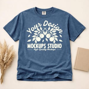 May include: A blue t-shirt with a white graphic design featuring the text "Your Design Mockups Studio High-Quality Mockups". The shirt is made of a soft, comfortable material.