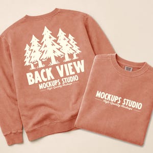 Może przedstawiać: Dwie koralowe bluzy. Jedna przedstawia białą grafikę drzew iglastych oraz napisy "BACK VIEW" i "MOCKUPS STUDIO". Na drugiej bluzie nadrukowano napis "MOCKUPS STUDIO".