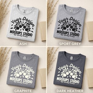 May include: Four folded t-shirts in ash, sport grey, graphite, and dark heather colors. Each shirt features a white graphic with the text "Your Design MOCKUPS STUDIO High-Quality Mockups".