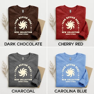 Puede incluir: Cuatro sudaderas de cuello redondo en chocolate oscuro, rojo cereza, carb&oacute;n y azul carolina. Cada sudadera presenta un gr&aacute;fico blanco con el texto "YOUR DESIGN HERE", "NEW COLLECTION" y "SHEMET.STUDIO".