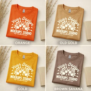 May include: Four folded t-shirts in orange, old gold, gold, and brown savanna colors. Each shirt has a white graphic with the text "Your Design MOCKUPS STUDIO High-Quality Mockups". The word "ORANGE", "OLD GOLD", "GOLD", and "BROWN SAVANA" are printed below each shirt.