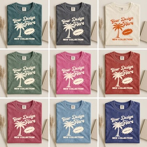 K&ouml;nnte beinhalten: Neun verschiedenfarbige T-Shirts mit dem Text "Your Design Here" und einer Palmen-Grafik. Die Shirts sind in verschiedenen Farben erh&auml;ltlich, darunter T&uuml;rkis, Grau, Creme, Gr&uuml;n, Pink, Rot und Blau. Auf jedem Shirt steht auch der Schriftzug "NEW COLLECTION!".