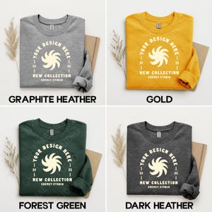 Puede incluir: Cuatro sudaderas de cuello redondo en gris grafito, dorado, verde bosque y gris oscuro. Cada sudadera presenta un dise&ntilde;o circular con el texto "YOUR DESIGN HERE" y "NEW COLLECTION SHEMET.STUDIO". Las sudaderas se muestran sobre un fondo neutro.