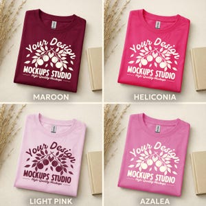 May include: Four t-shirts in different colors: maroon, heliconia, light pink, and azalea. Each shirt has a white graphic with the text "Your Design MOCKUPS STUDIO High-Quality Mockups". The shirts are folded and displayed with small books and dried plants.