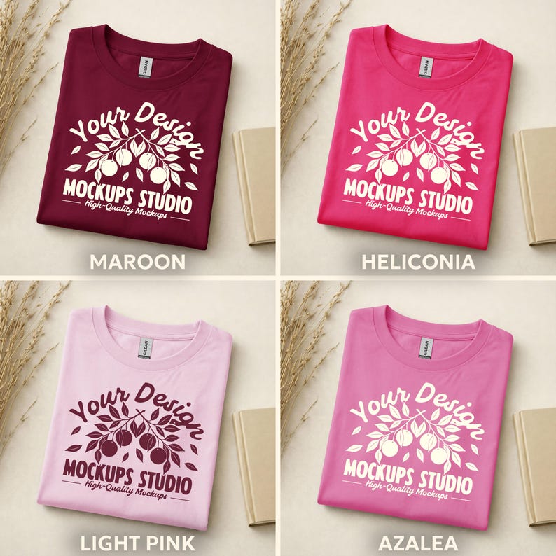 May include: Four t-shirts in different colors: maroon, heliconia, light pink, and azalea. Each shirt has a white graphic with the text "Your Design MOCKUPS STUDIO High-Quality Mockups". The shirts are folded and displayed with small books and dried plants.