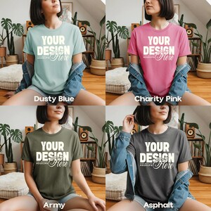May include: Four t-shirts in different colors: dusty blue, charity pink, army green, and asphalt gray. Each shirt has the text "YOUR DESIGN Here" printed on the front. The shirts are short-sleeved and appear to be made of a soft material.