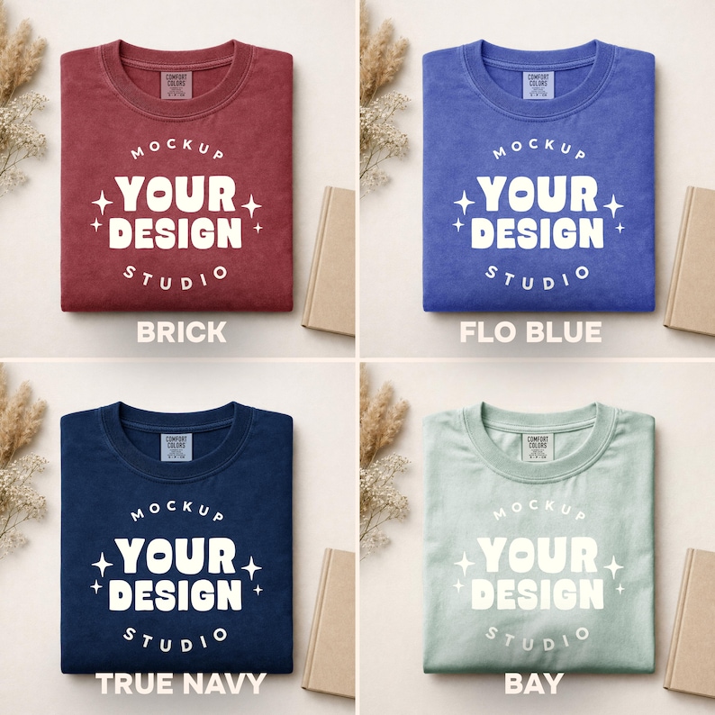 Peut inclure: Quatre t-shirts de couleurs diff&eacute;rentes : rouge brique, bleu, marine et vert clair. Chaque t-shirt porte l'inscription blanche "MOCKUP YOUR DESIGN STUDIO". Les t-shirts sont pr&eacute;sent&eacute;s sur un fond neutre avec un livre et des plantes d&eacute;coratives.