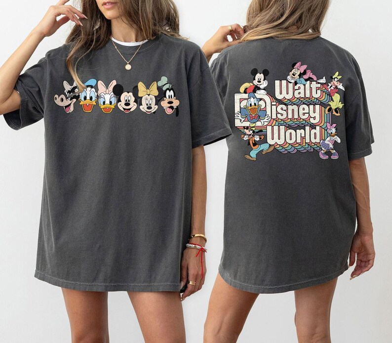Pu&ograve; includere: T-shirt grigio scuro con personaggi Disney sul davanti, tra cui Pippo, Paperino, Paperina, Minnie Mouse e Topolino. La parte posteriore della maglietta mostra le parole "Walt Disney World" con personaggi e un design arcobaleno.