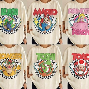 May include: A collection of six off-white t-shirts featuring graphic prints of Nintendo characters including Luigi, Mario, Princess Peach, Bowser, Yoshi, and Toad. Each shirt displays the character name, a checkered circle, and lightning bolts.