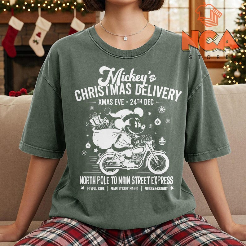 May include: A green t-shirt with a white graphic of Mickey Mouse on a motorbike, carrying gifts. Text reads "Mickey's Christmas Delivery" and "North Pole to Main Street Express". The shirt has a faded, vintage appearance.