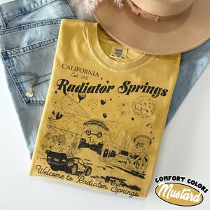 May include: A white ceramic mug with a black handle and the text "But First, Coffee" in a bold, black font. The mug is set against a neutral background, highlighting its simple design.