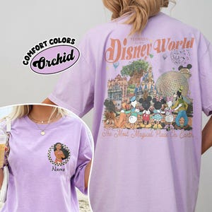 May include: A lilac t-shirt featuring a Disney World graphic on the back, with the text "Disney World Florida Est. 1971" and Disney characters. The front of the shirt has a small graphic with the text "Name".
