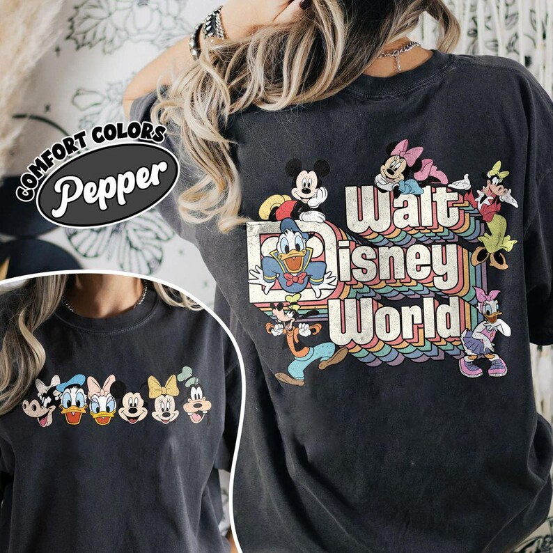 Pu&ograve; includere: T-shirt grigio scuro con la scritta "Walt Disney World" in un design arcobaleno retr&ograve;, con personaggi dei cartoni animati come Topolino e Paperino. La maglietta ha anche la scritta "Comfort Colors Pepper" in un ovale nero.