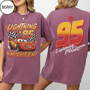 K&ouml;nnte beinhalten: Beerenfarbenes T-Shirt mit Lightning McQueen aus dem Film Cars. Die Grafik auf der Vorderseite zeigt das Auto, die Nummer 95 und den Text "Lightning McQueen". Auf der R&uuml;ckseite ist eine gro&szlig;e 95 und der Text "Lightning McQueen" zu sehen.