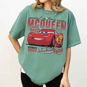 Puede incluir: Una camiseta verde con un dise&ntilde;o de Rayo McQueen de la pel&iacute;cula Cars. El dise&ntilde;o incluye el texto "Lightning McQueen est. 1977", "Ultimate Speed", "Think Fast" y "Rust-eze". La camiseta tiene mangas cortas y un corte holgado.