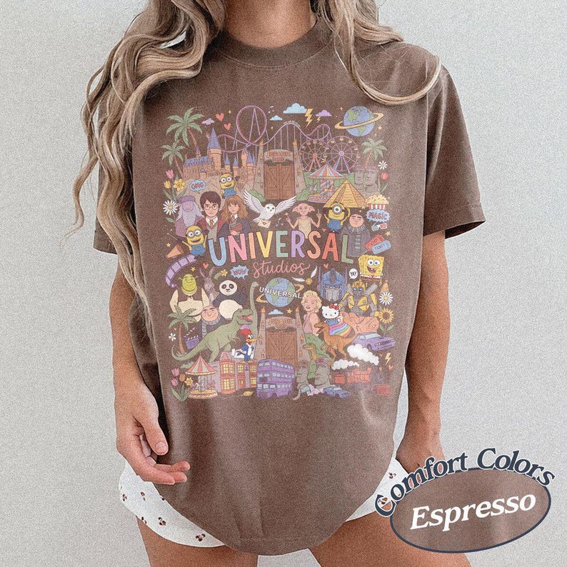 Może przedstawiać: Brązowy t-shirt z kr&oacute;tkim rękawem z kolorowym nadrukiem graficznym przedstawiającym postacie i atrakcje Universal Studios. Wz&oacute;r zawiera ilustracje Harry'ego Pottera, Shreka, Minionk&oacute;w oraz r&oacute;żnych element&oacute;w parku rozrywki z napisem Universal Studios.