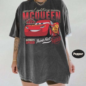 Puede incluir: Camiseta gris oscuro con un dise&ntilde;o de Rayo McQueen de la pel&iacute;cula Cars. El dise&ntilde;o incluye el texto "Lightning McQueen" y "Ultimate Speed Think Fast". El n&uacute;mero 95 es visible en el coche.