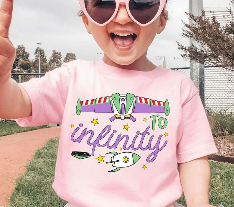 Puede incluir: Una camiseta rosa claro con un gr&aacute;fico colorido de una nave espacial y la frase "To infinity" en una fuente caprichosa. El dise&ntilde;o incluye estrellas y un cohete, creando un aspecto divertido. Esta camiseta infantil es perfecta para los fan&aacute;ticos del espacio y la aventura.
