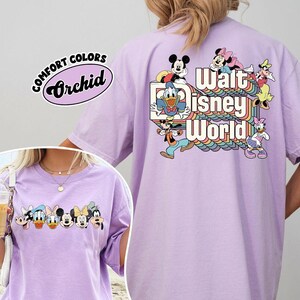 Pu&ograve; includere: Una maglietta lilla Comfort Colors con una grafica colorata di personaggi Disney e la scritta "Walt Disney World". La parte anteriore della maglietta presenta una grafica pi&ugrave; piccola dei personaggi. La maglietta ha maniche corte e girocollo.