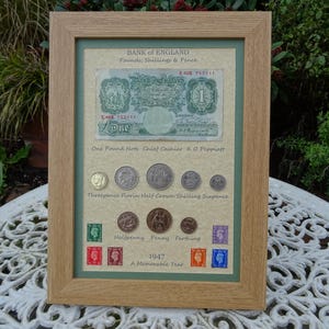 79.º aniversario del nacimiento de Britannia, 1947. Billete de 1 libra, 8 monedas y sellos enmarcados.
