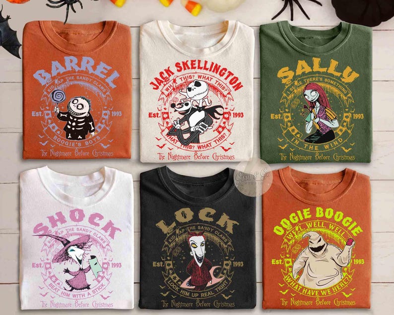 Op de afbeelding: Zes t-shirts met personages uit The Nightmare Before Christmas. De kleuren zijn oranje, cr&egrave;me, olijfgroen, wit, zwart en roest. Elk t-shirt toont een personageafbeelding, een naam en filmgerelateerde tekst zoals Est. 1993.