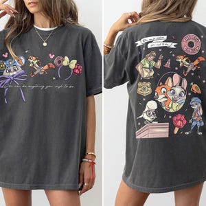 Puede incluir: Camiseta gris oscuro con personajes de dibujos animados y el texto "You can be anything you wish to be." La parte trasera de la camiseta tiene m&aacute;s personajes de dibujos animados y las palabras "The Big Donut."