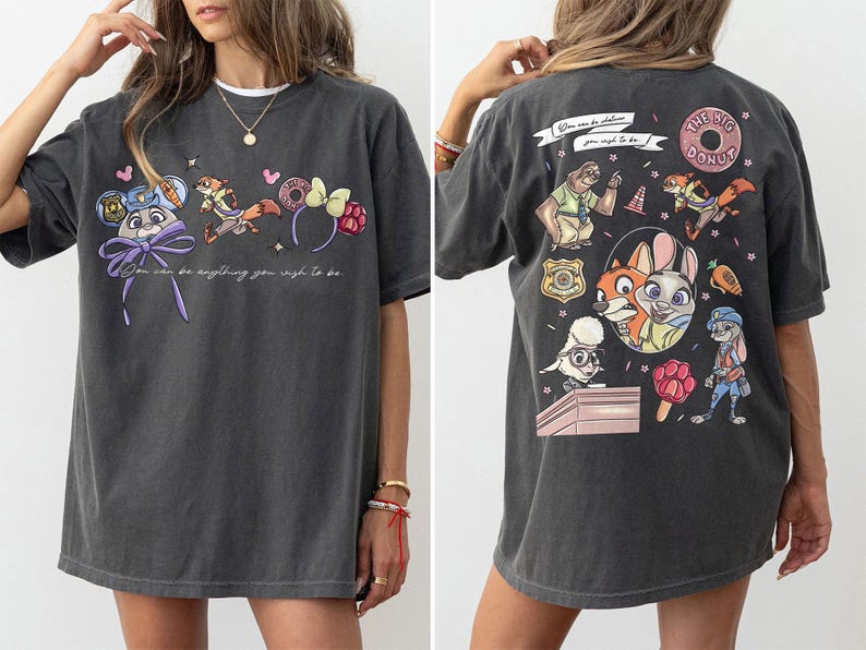 Puede incluir: Camiseta gris oscuro con personajes de dibujos animados y el texto "You can be anything you wish to be." La parte trasera de la camiseta tiene m&aacute;s personajes de dibujos animados y las palabras "The Big Donut."