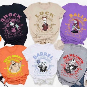 Op de afbeelding: Zes T-shirts met korte mouwen en ronde hals met personages uit The Nightmare Before Christmas. De kleuren zijn zwart, beige, paars, oranje, wit en grijs. Elk shirt toont een unieke karakterafbeelding met tekst en een cirkelvormige rand.