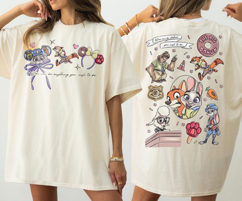 Puede incluir: Camiseta color crema con personajes de dibujos animados y texto. La parte delantera muestra personajes con diademas y la frase "You can be anything you wish to be." La parte trasera muestra m&aacute;s personajes y "The Big Donut."