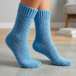 May include: A pair of light blue knitted socks. The socks are a solid color with a ribbed cuff and a textured, waffle-like pattern on the body. The socks are designed to be worn on the feet.