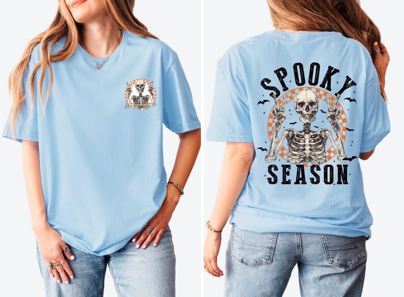 Puede incluir: Camiseta azul claro con un gr&aacute;fico de esqueleto. La parte delantera presenta un peque&ntilde;o dise&ntilde;o de esqueleto, mientras que la parte trasera muestra un esqueleto m&aacute;s grande con las palabras "Spooky Season" e ilustraciones de murci&eacute;lagos. Una prenda con tem&aacute;tica de Halloween.