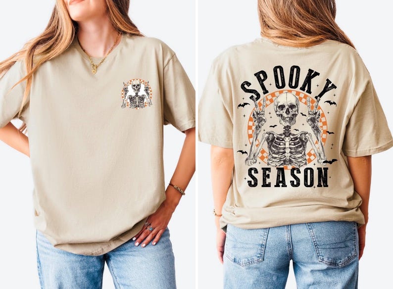 Puede incluir: Camiseta beige con un gr&aacute;fico de esqueleto en la parte delantera y trasera. La parte delantera presenta un peque&ntilde;o dise&ntilde;o de esqueleto, mientras que la parte trasera muestra un esqueleto m&aacute;s grande con las palabras "Spooky Season" e ilustraciones de murci&eacute;lagos. Prenda de vestir con tem&aacute;tica de Halloween.