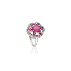 Op de afbeelding: Een zilveren ring met een grote ovale roze edelsteen in het midden, omringd door kleinere roze edelstenen en heldere accentstenen. De ring heeft een bloemmotief en een gepolijste band.