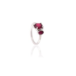 May include: A silver ring featuring two oval-shaped, deep red gemstones. The larger stone is set at the top, with a smaller stone below it. The ring is set against a white background.