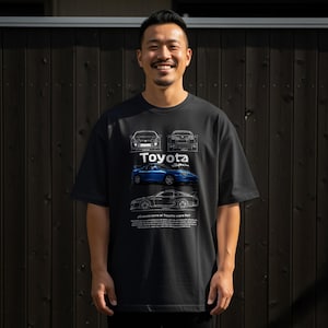 May include: Black t-shirt featuring a Toyota Supra design. The shirt displays the Toyota logo, car blueprints, and a blue Supra car graphic. The text "¿Cuanto corre el Toyota supra Rz?" is also visible.