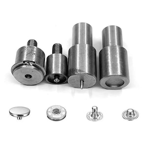 May include: A collection of metal tools and fasteners, including various cylindrical punches and snap components. The tools have threaded ends and spring mechanisms. The fasteners include a domed button, a toothed ring, and two snap-style pieces.
