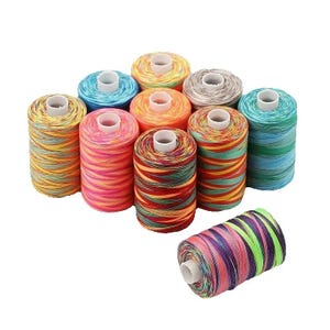 May include: A collection of colorful spools of thread, each wound with a variety of vibrant hues. The threads are arranged in a cluster, with a single spool positioned separately. The colors include shades of blue, green, yellow, orange, pink, and red.