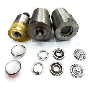 Peut inclure: Ensemble d'outils de pose de boutons-pression en métal et de boutons-pression. Les outils sont cylindriques, l'un d'eux ayant une pointe en caoutchouc jaune. Les boutons-pression comprennent des dessus bombés blancs, des anneaux métalliques et des dos à pression.
