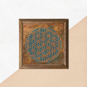 May include: Square wooden wall art featuring a teal and gold geometric design. The artwork has a circular pattern in the center, framed by a rustic brown wooden frame. The background has a textured, mottled appearance.