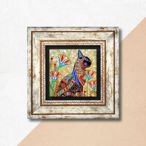 May include: Framed artwork depicting an Egyptian cat with detailed patterns in black, red, blue, and gold. The cat is set amongst colourful lotus flowers. The frame is distressed white with a gold inner border.