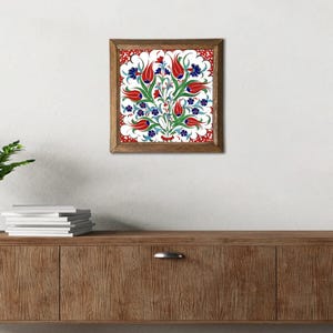 May include: A framed square wall art piece featuring a floral design. The artwork showcases red tulips, blue flowers, and green leaves against a white background, framed with a brown wooden border. The design is reminiscent of traditional Turkish art.