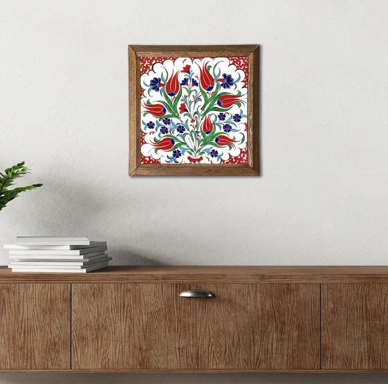 May include: A framed square wall art piece featuring a floral design. The artwork showcases red tulips, blue flowers, and green leaves against a white background, framed with a brown wooden border. The design is reminiscent of traditional Turkish art.