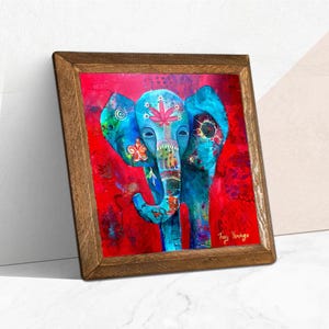 Puede incluir: Una impresi&oacute;n art&iacute;stica enmarcada que presenta un elefante vibrante y estilizado sobre un fondo rojo. El elefante est&aacute; pintado en tonos azules, adornado con patrones florales y de hojas. El marco de madera a&ntilde;ade un toque r&uacute;stico a la obra.