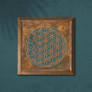 May include: Square wooden framed wall art featuring a detailed gold-colored geometric pattern on a teal background. The artwork is set against a textured, copper-toned surface, and the frame is made of natural wood.