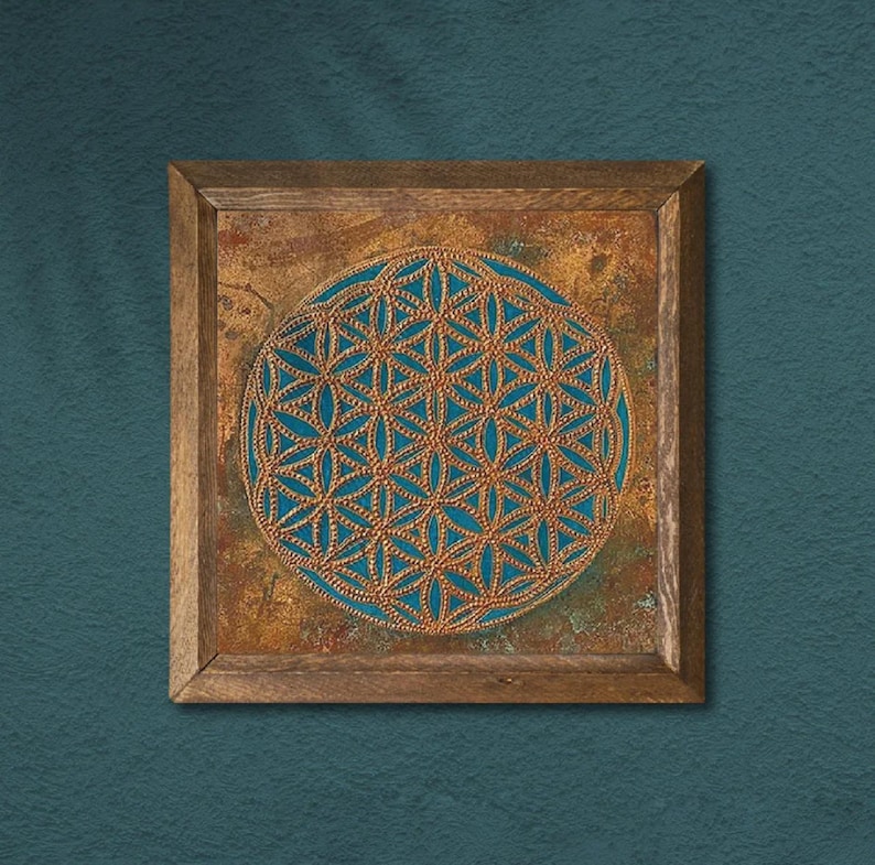 May include: Square wooden framed wall art featuring a detailed gold-colored geometric pattern on a teal background. The artwork is set against a textured, copper-toned surface, and the frame is made of natural wood.